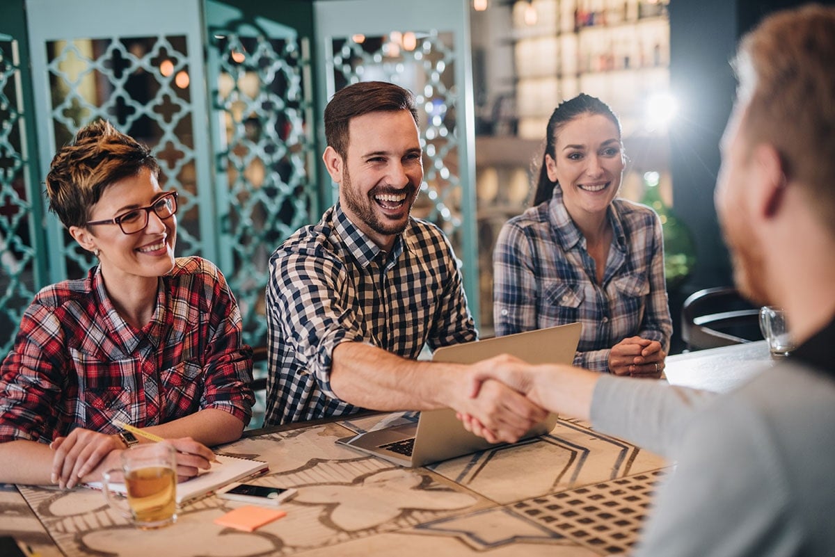 Man shaking hands over a table with other colleagues