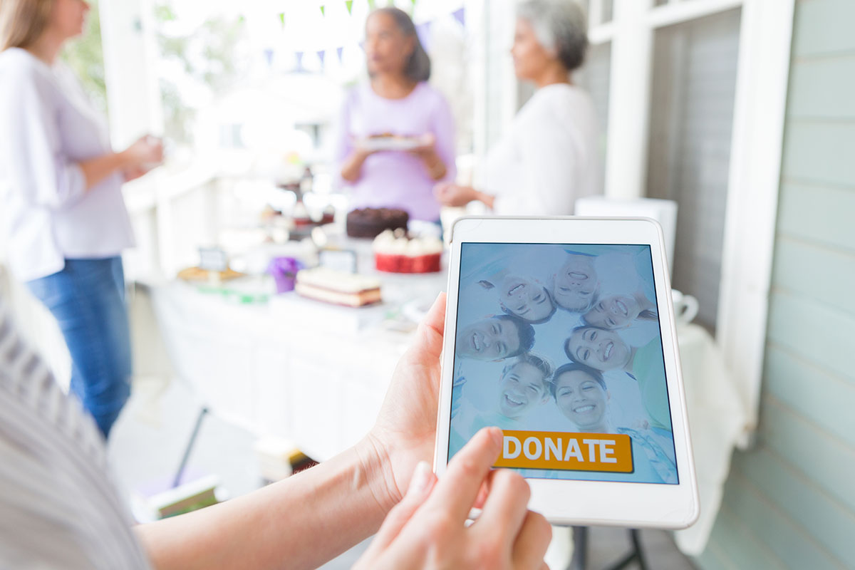 Hands about to press a donate button on a tablet device