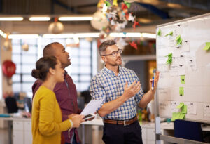 Manager showing two colleagues work on a whiteboard