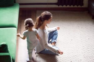 Woman meditating whilst toddler plays.