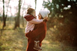 Woman holding a child in the woods.