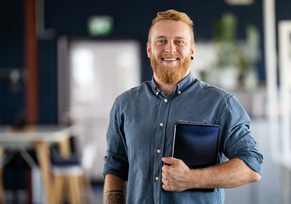 A digital marketer is holding his tablet in a marketing agency