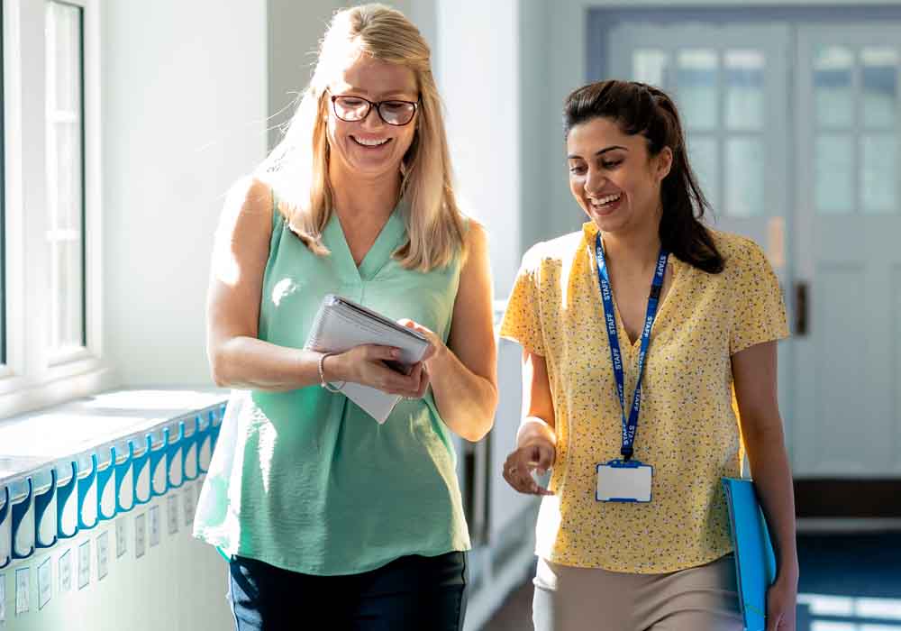 A Healthcare Manager and a colleague are talking in a hallway