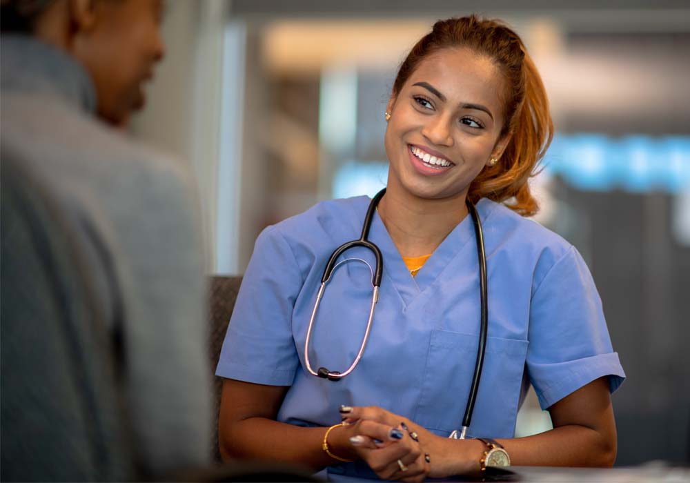A young health and social care leader is talking in a hospital setting