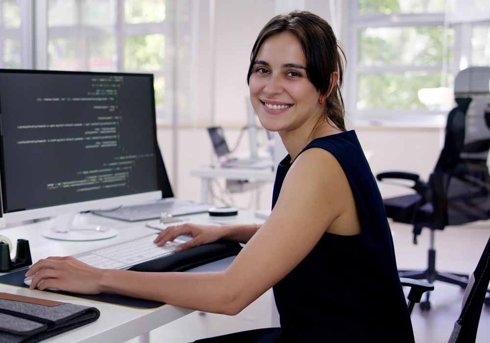 Female embedded computing expert is working in the office with multiple coding screens