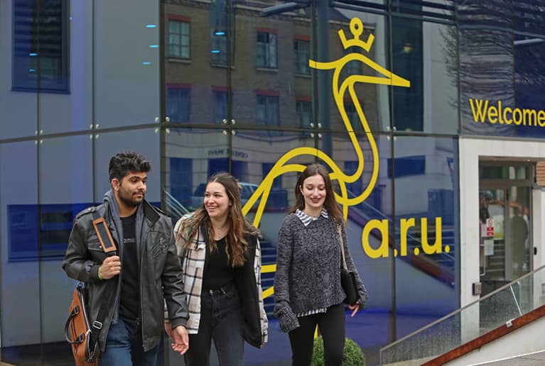 About ARU - students standing in front of Anglia Ruskin University